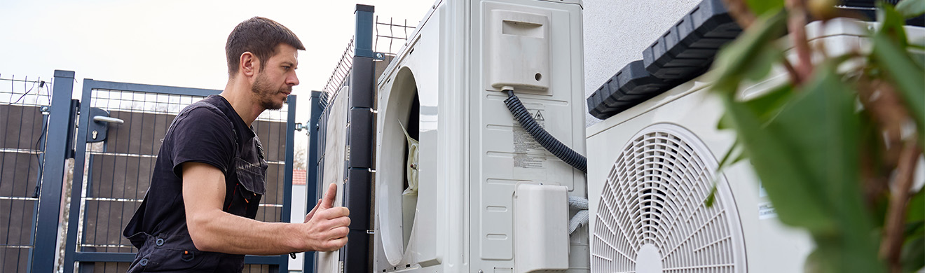 Techniker wartet eine Luft-Wasser-Wärmepumpe an einem Wohngebäude und prüft die Anlage fachgerecht für effizienten Heizungsbau in Aachen.