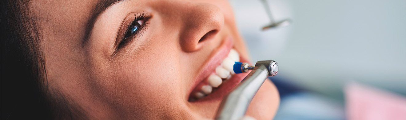 Junge Frau erhält professionelle Zahnreinigung in Aachen beim Zahnarzt, entspannt im Behandlungsstuhl, Zahnstein wird entfernt.