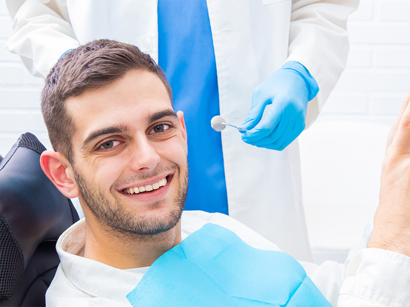 Patient betrachtet Zähne im Spiegel nach Zahnprophylaxe in Aachen beim Zahnarzt, gepflegtes und gesundes Lächeln.