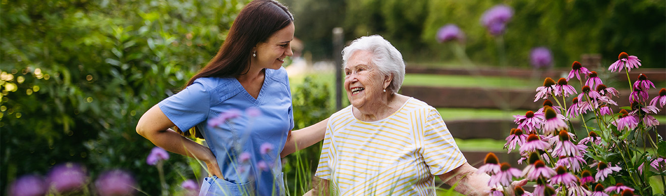 Seniorin sitzt mit ihrer Betreuungskraft im Garten und genießt persönliche Unterstützung und gemeinsame Zeit im Freien.